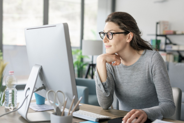 Vrouw met bril werkt op kantoor achter een computer.